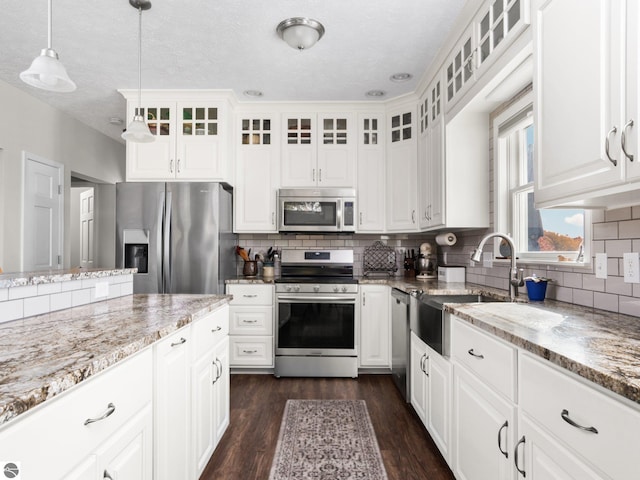 kitchen featuring white cabinets, light stone countertops, dark hardwood / wood-style floors, stainless steel appliances, and decorative light fixtures