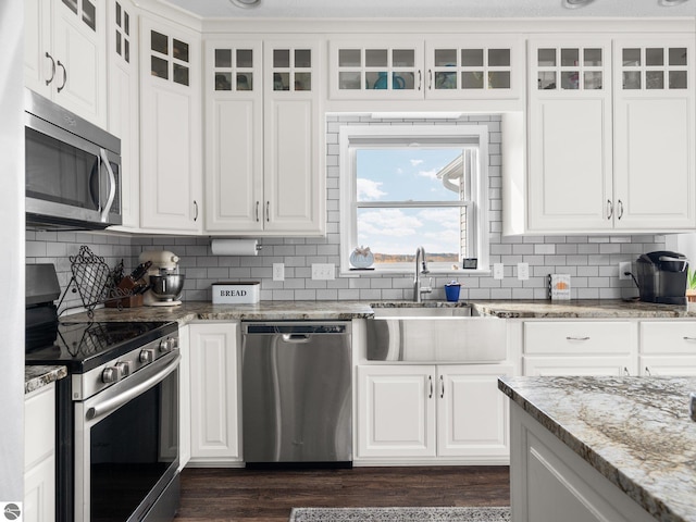 kitchen with stone counters, white cabinets, stainless steel appliances, and sink