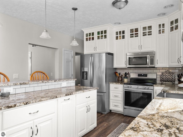 kitchen with white cabinetry, stainless steel appliances, hanging light fixtures, and backsplash