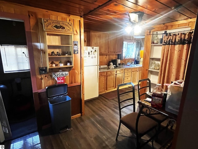 kitchen featuring white fridge, dark hardwood / wood-style floors, wooden walls, wooden ceiling, and ceiling fan