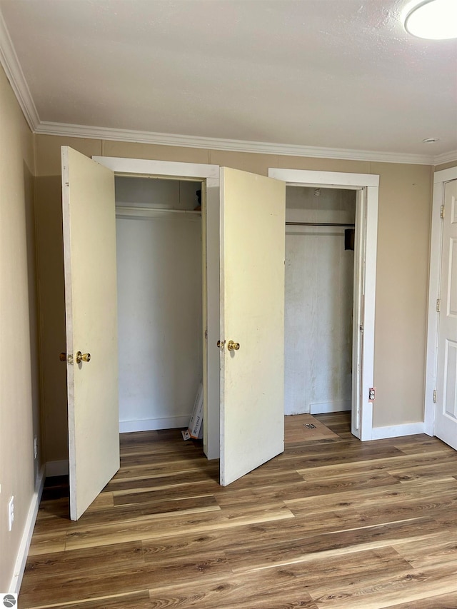 unfurnished bedroom featuring ornamental molding, dark wood-type flooring, and a closet