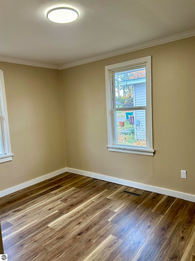 spare room with hardwood / wood-style floors and crown molding