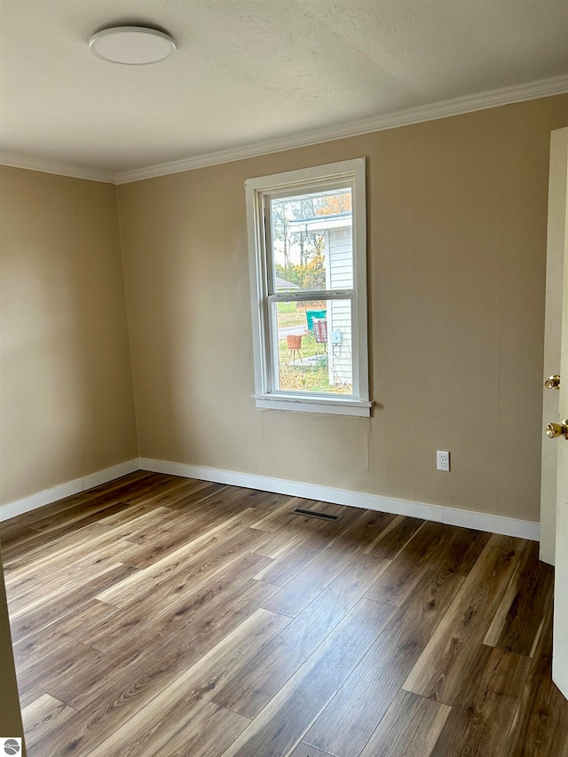 spare room featuring crown molding and wood-type flooring