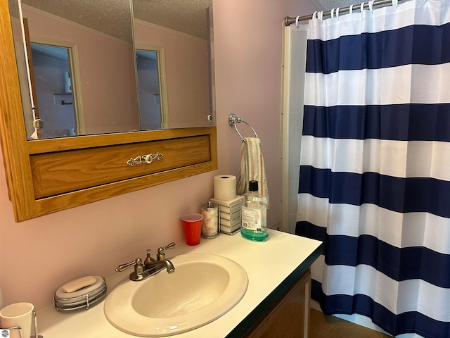 full bathroom featuring curtained shower, ornamental molding, vanity, and a textured ceiling