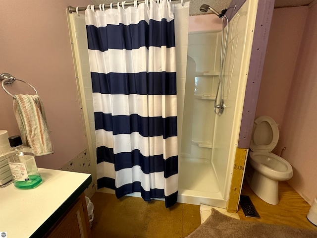 bathroom with vanity, a shower stall, and toilet