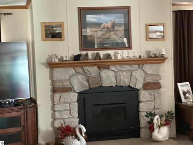 interior details with a stone fireplace and ornamental molding