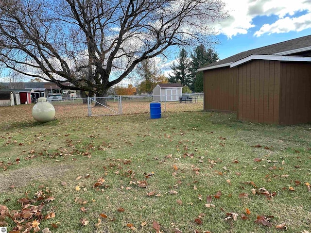 view of yard featuring an outbuilding, a storage shed, and fence