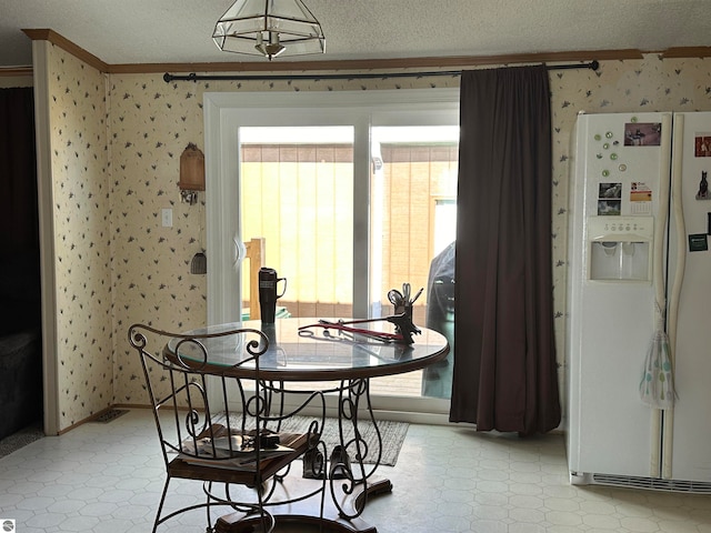 dining space with wallpapered walls, plenty of natural light, light floors, and a textured ceiling