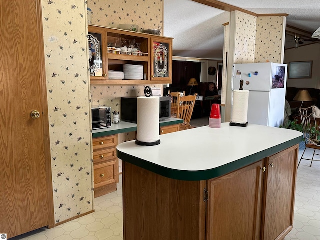 kitchen featuring light floors, built in study area, wallpapered walls, a toaster, and freestanding refrigerator