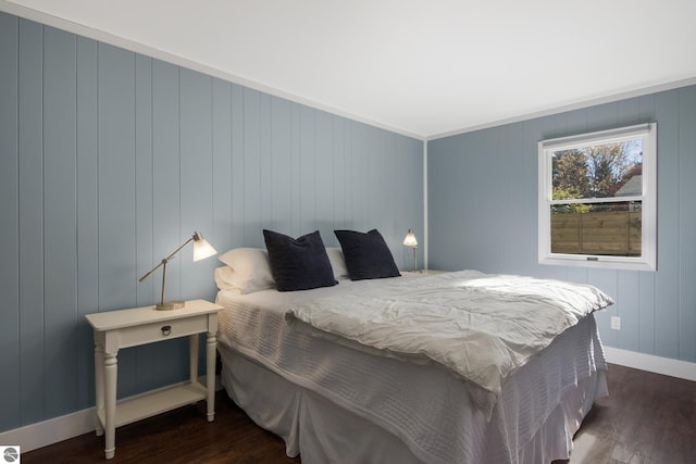 bedroom with ornamental molding, wood walls, and dark wood-type flooring