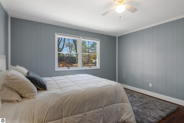 bedroom featuring ceiling fan, wood walls, ornamental molding, and hardwood / wood-style floors