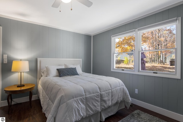 bedroom featuring ornamental molding, ceiling fan, wooden walls, and dark hardwood / wood-style flooring