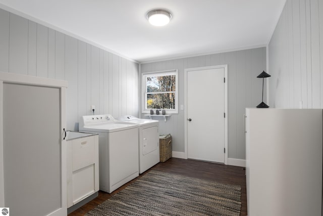 washroom featuring dark hardwood / wood-style floors, wooden walls, and washer and clothes dryer