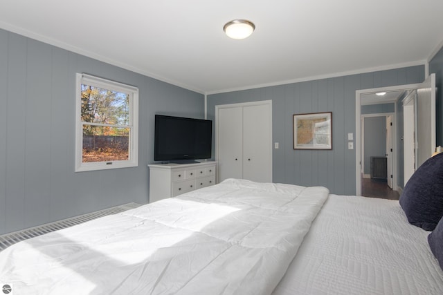 bedroom featuring ornamental molding, wood-type flooring, and a closet