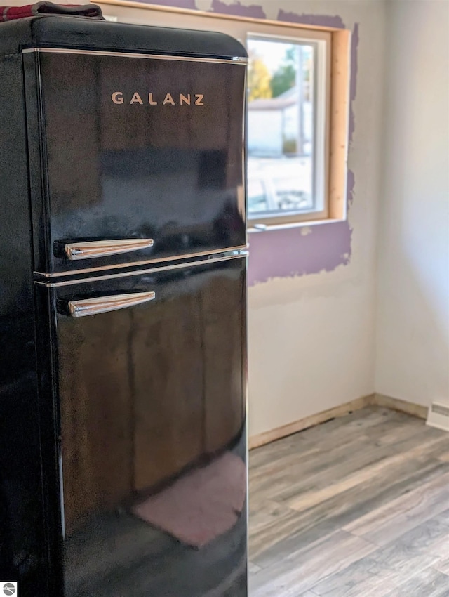 kitchen with hardwood / wood-style floors and black fridge