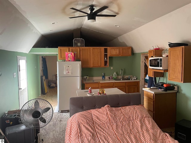 kitchen featuring ceiling fan, wood-type flooring, vaulted ceiling, sink, and white refrigerator