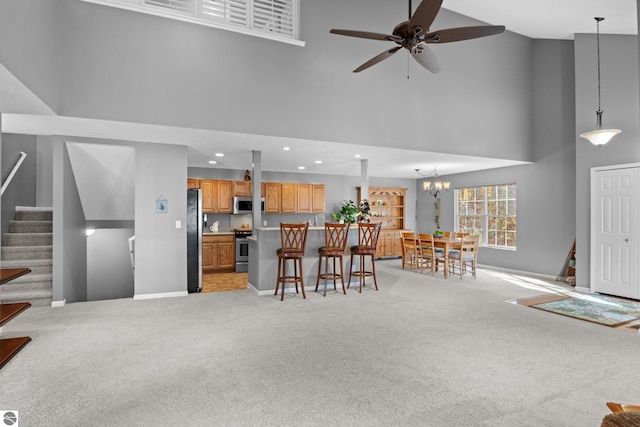 living room featuring light carpet, a high ceiling, and ceiling fan with notable chandelier