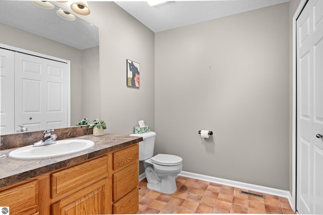 bathroom with vanity, toilet, and a textured ceiling