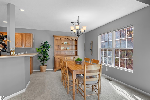 dining area with an inviting chandelier and light colored carpet