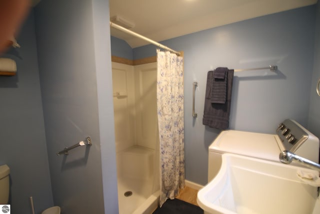 bathroom featuring a sink, a shower stall, washing machine and clothes dryer, and baseboards