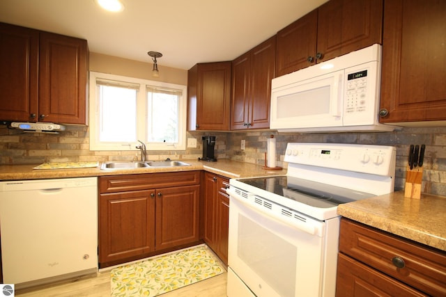 kitchen featuring white appliances, a sink, backsplash, light wood-style flooring, and light countertops