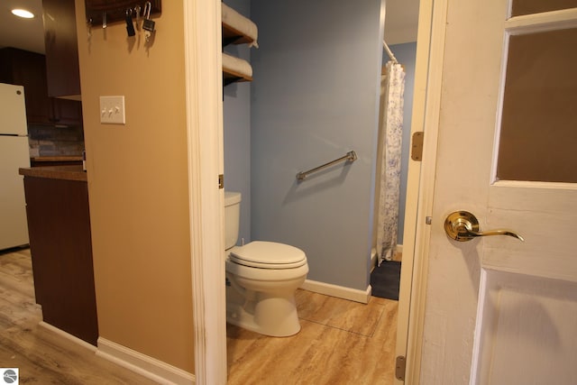 full bath featuring wood finished floors, toilet, curtained shower, and baseboards