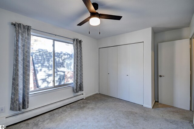 unfurnished bedroom featuring a closet, ceiling fan, light carpet, and a baseboard heating unit