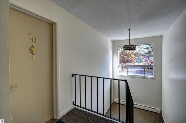 stairs featuring a textured ceiling, baseboard heating, and carpet flooring