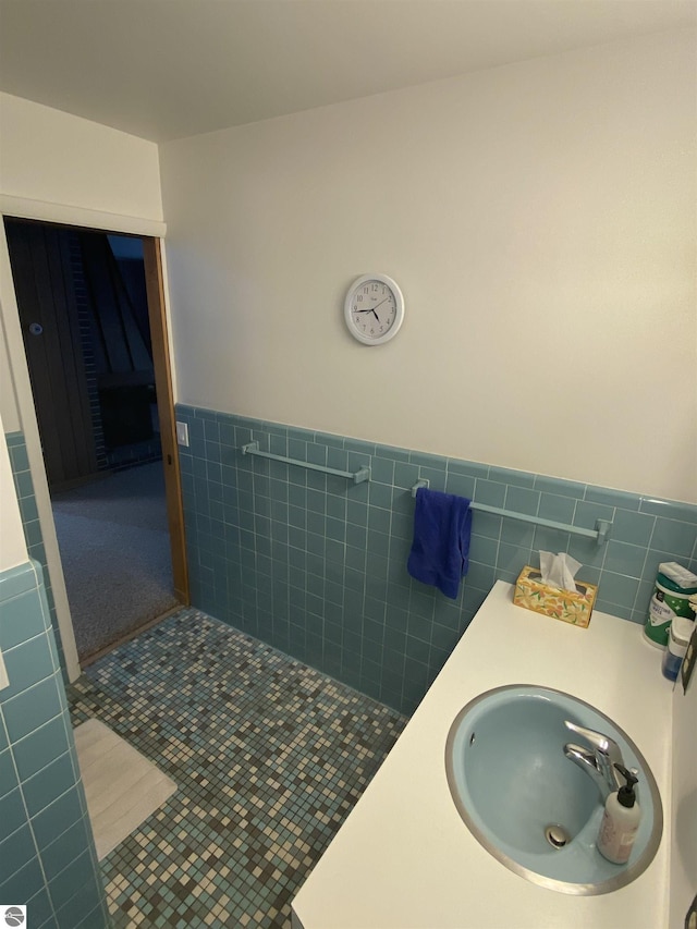 616 Holiday Dr, Bellaire, MI 49615 - bathroom with tile walls, a sink, a wainscoted wall, and tile patterned floors
