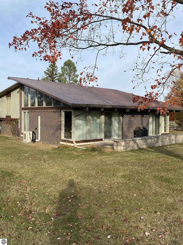 616 Holiday Dr, Bellaire, MI 49615 - rear view of property featuring brick siding, a yard, and metal roof