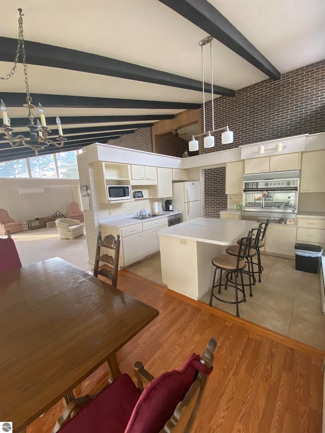 dining space featuring an inviting chandelier, light hardwood / wood-style flooring, beamed ceiling, and sink