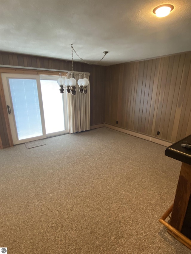 616 Holiday Dr, Bellaire, MI 49615 - unfurnished room featuring wooden walls, a chandelier, and carpet floors