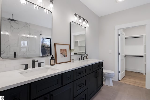 bathroom featuring backsplash, wood-type flooring, toilet, vanity, and a shower with shower door