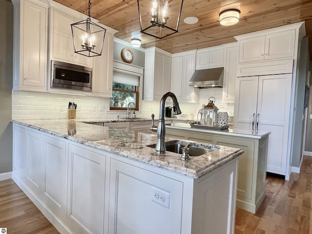 11320 Shippey Ln, Rapid City, MI 49676 - kitchen featuring wood finished floors, stainless steel microwave, under cabinet range hood, wooden ceiling, and a notable chandelier
