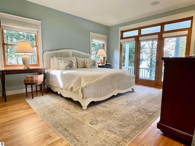 bedroom featuring multiple windows, access to outside, and hardwood / wood-style flooring