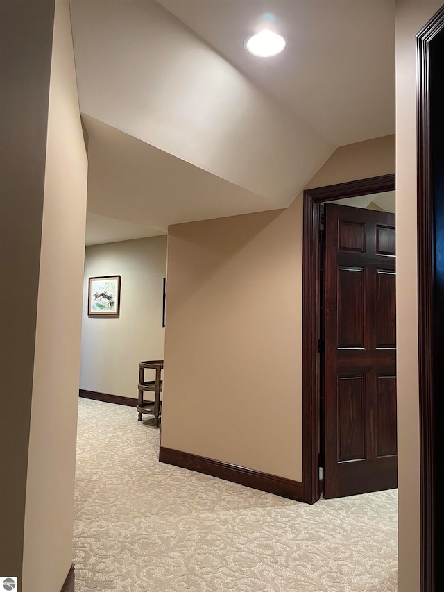 corridor featuring lofted ceiling and light carpet