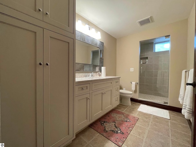 bathroom with toilet, vanity, tile patterned floors, and tiled shower