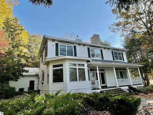 11320 Shippey Ln, Rapid City, MI 49676 - view of front of home featuring a porch, a chimney, and central air condition unit