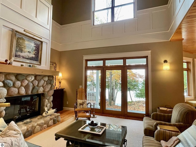 living room featuring a stone fireplace, wood-type flooring, a high ceiling, and a wealth of natural light