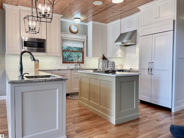 kitchen featuring wood ceiling, stainless steel microwave, pendant lighting, a center island, and ventilation hood