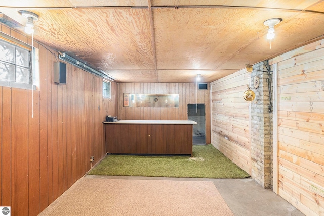 bar with wooden walls, concrete flooring, wooden ceiling, and plenty of natural light