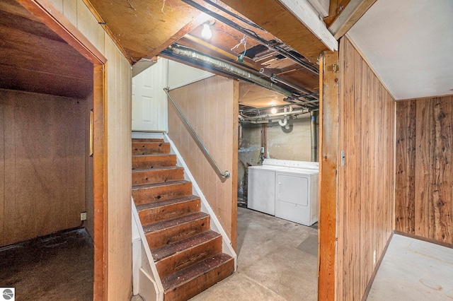 basement featuring wood walls and washing machine and clothes dryer