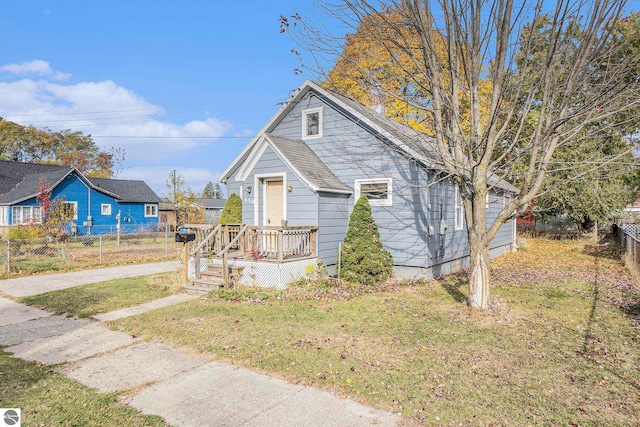 bungalow with a wooden deck and a front yard