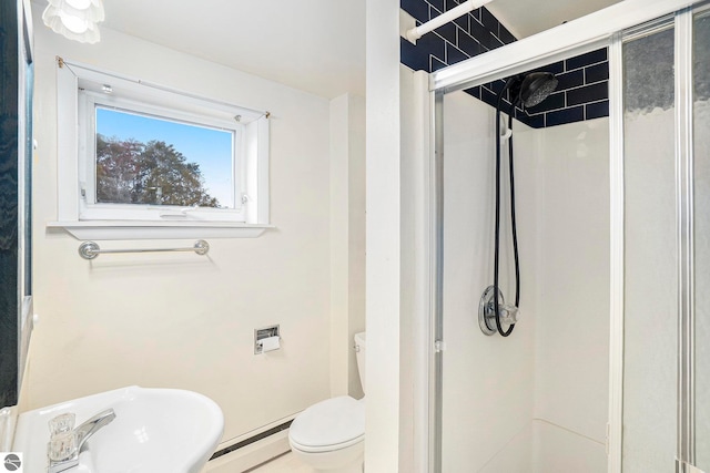 bathroom with toilet, a shower with shower door, and a baseboard heating unit