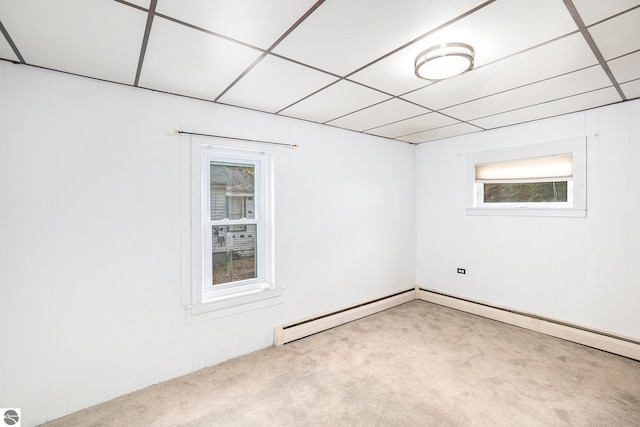 basement with a paneled ceiling and light colored carpet