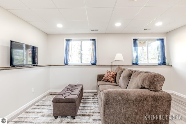 living room with a drop ceiling, a healthy amount of sunlight, and hardwood / wood-style flooring