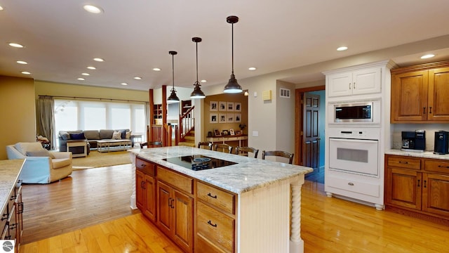 kitchen featuring white oven, a kitchen breakfast bar, light hardwood / wood-style flooring, black electric stovetop, and a center island