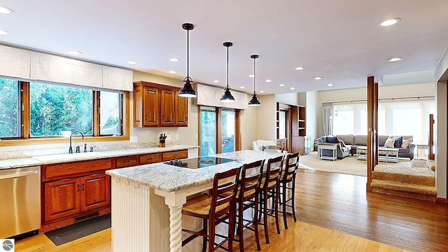 kitchen featuring stainless steel dishwasher, a breakfast bar, a healthy amount of sunlight, and a kitchen island