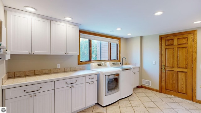 washroom featuring sink, light tile patterned flooring, separate washer and dryer, and cabinets