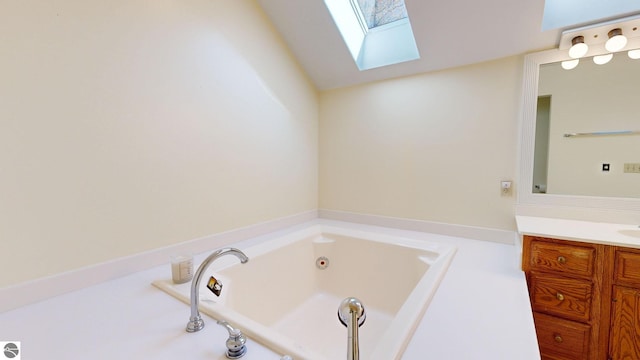 bathroom featuring vanity, vaulted ceiling with skylight, and a bathtub